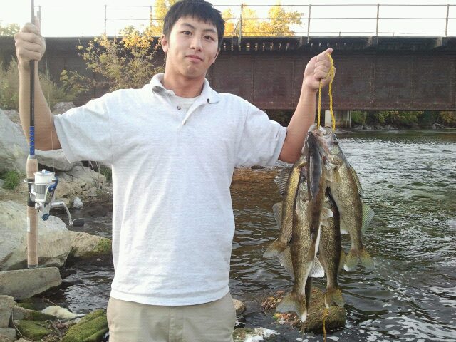 Dude holding up rod on one hand and walleyes on the other.